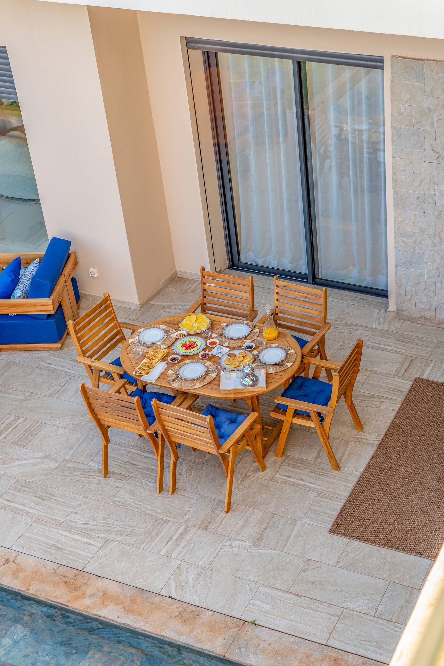 Wooden outdoor dining set with plates and cutlery on a patio.